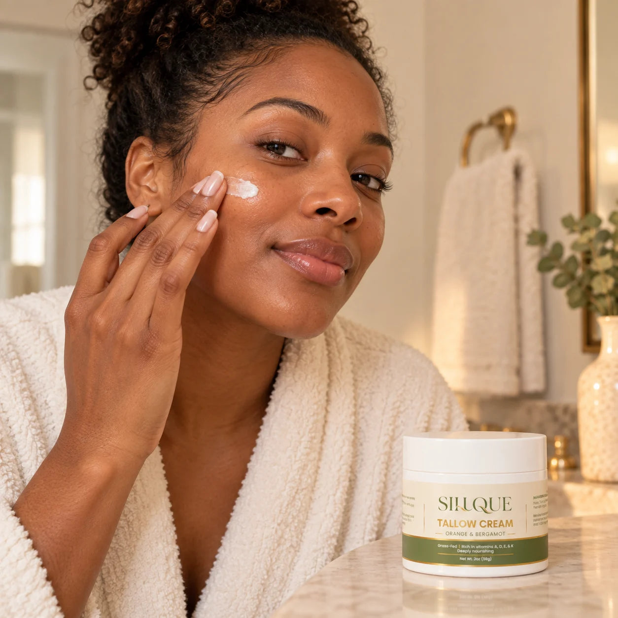 Black woman applying a small amount of Sillque Tallow Cream to her cheek